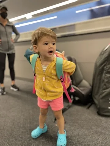 Zoe standing at the airport with a backpack and teal shoes