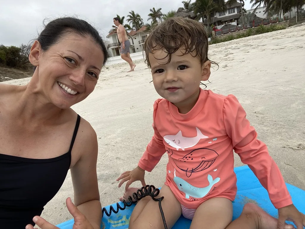 Marie and Zoe sitting on the beach with a blue board