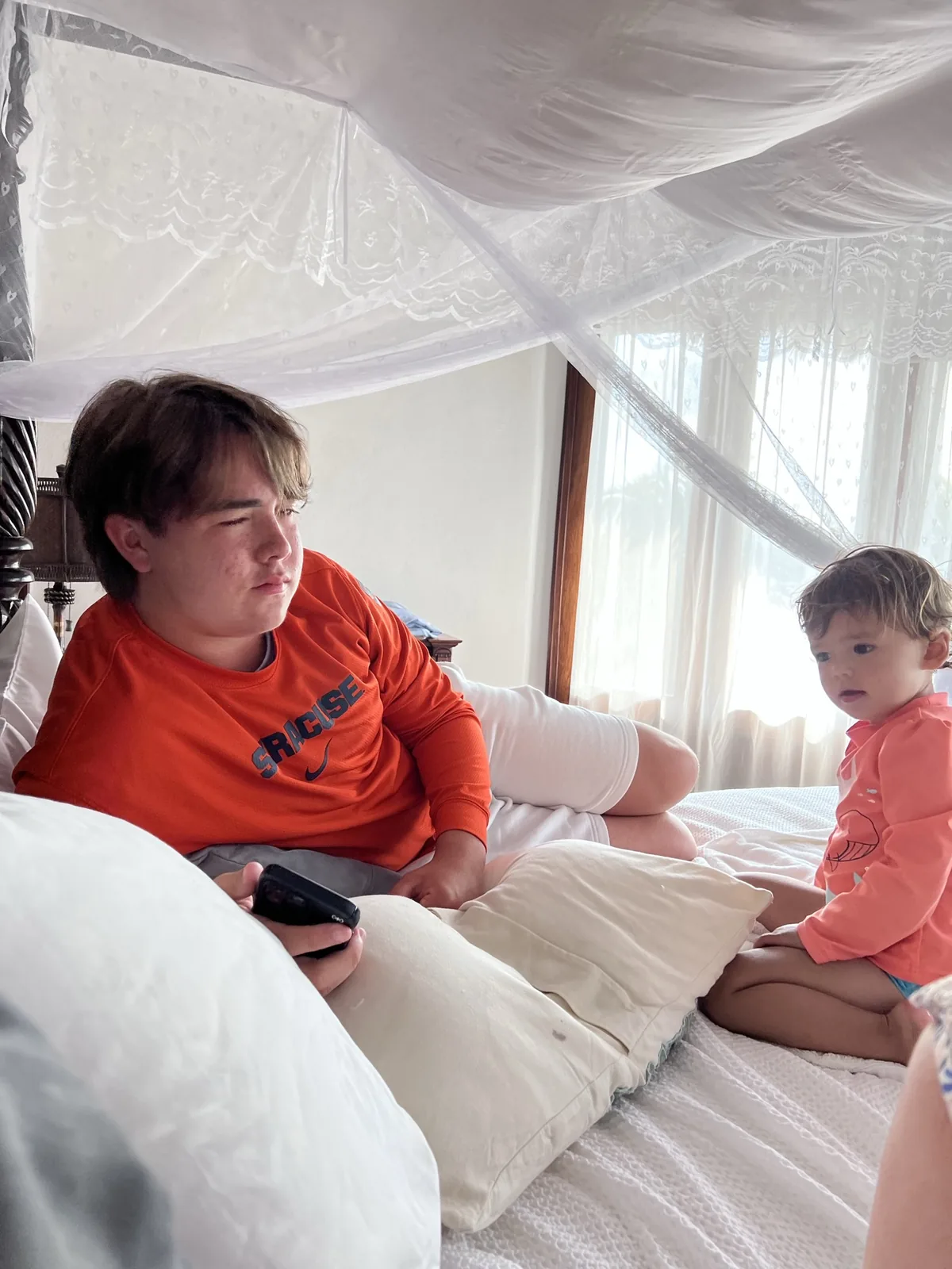 Zoe sitting on a bed beside an older family member
