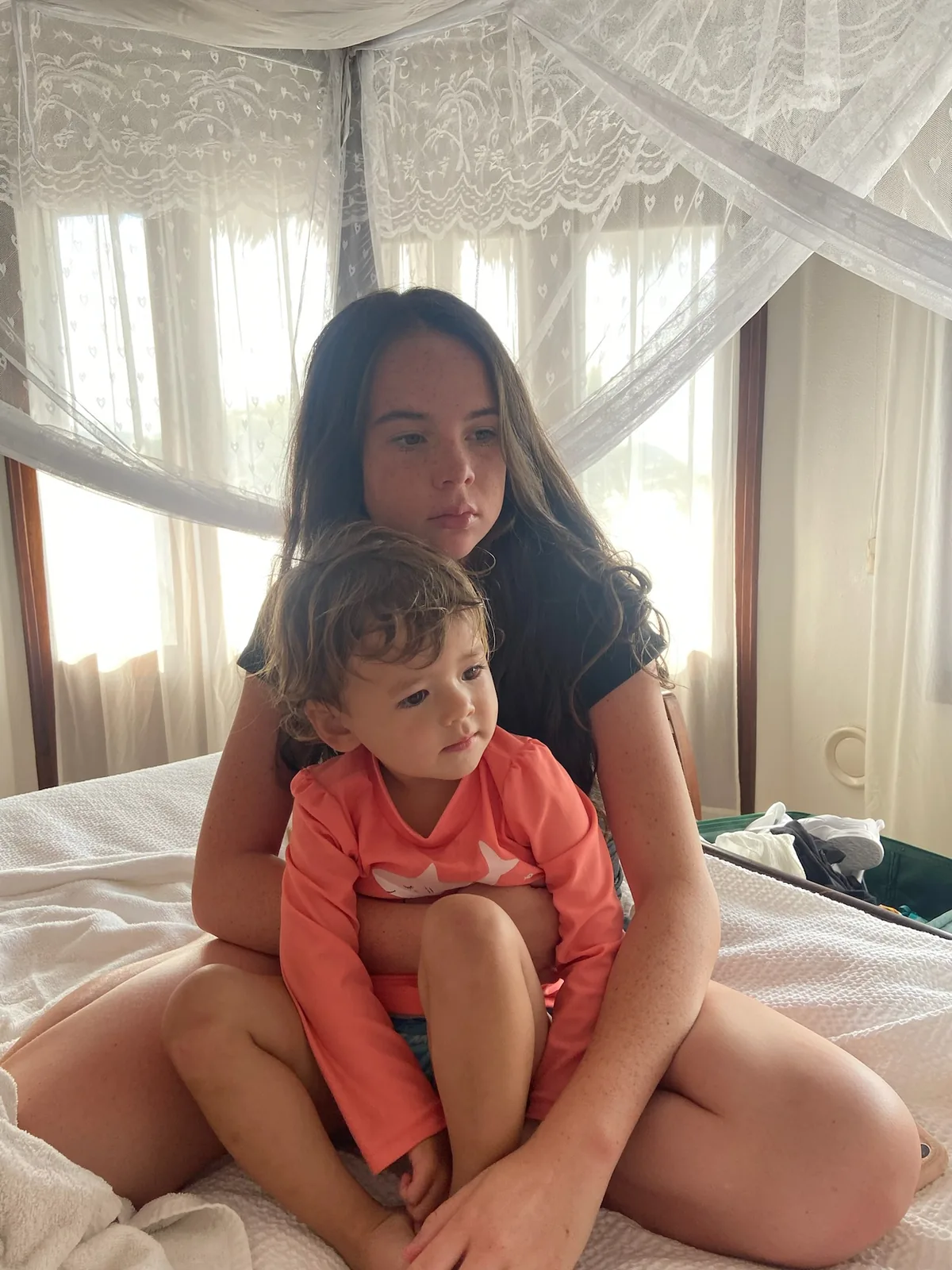 Zoe sitting on a bed with an older family member