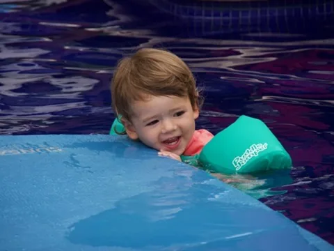 Zoe smiling in a green pool float