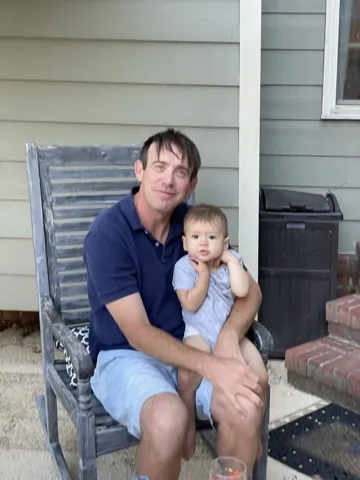 Zoe sitting on a relative's lap on a patio