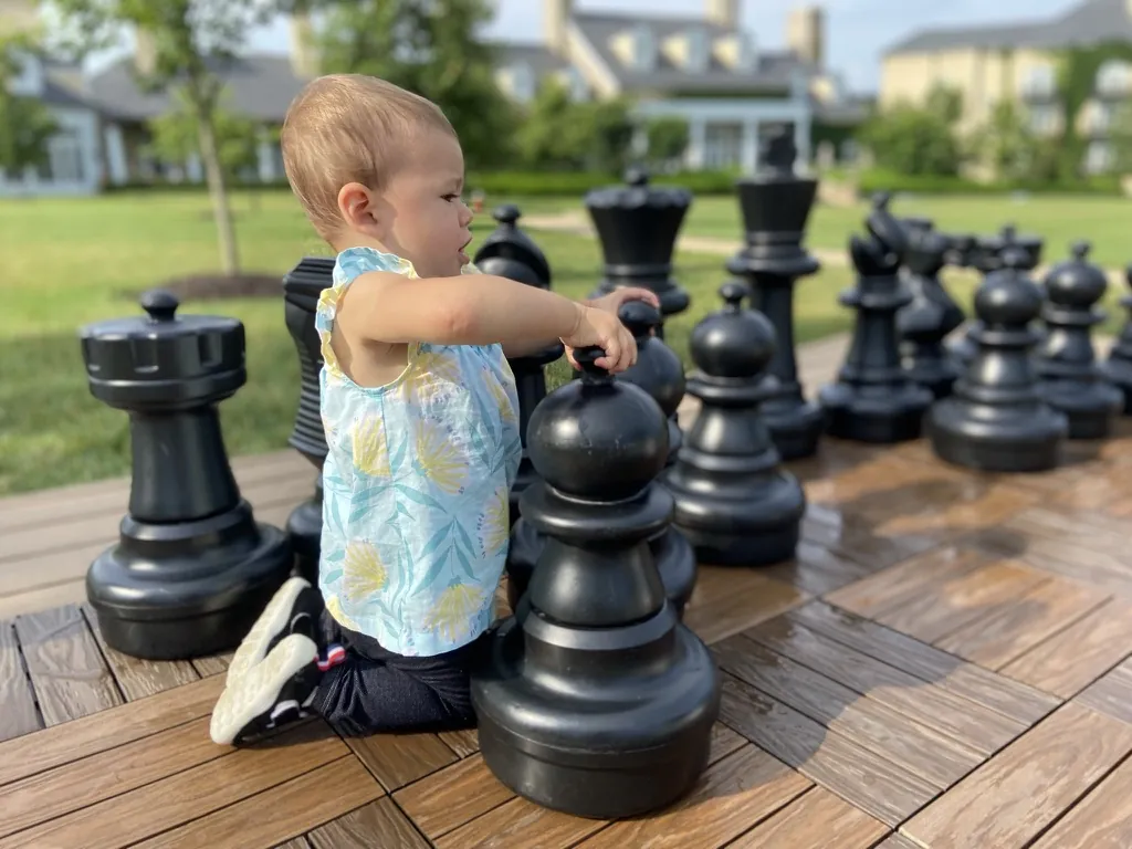 Zoe kneeling beside oversized chess pieces