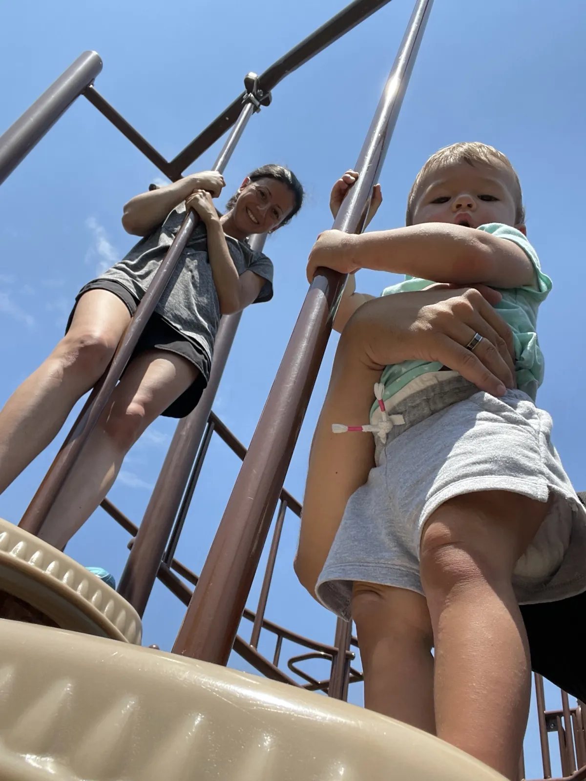 Marie and Zoe climbing on playground bars under a blue sky