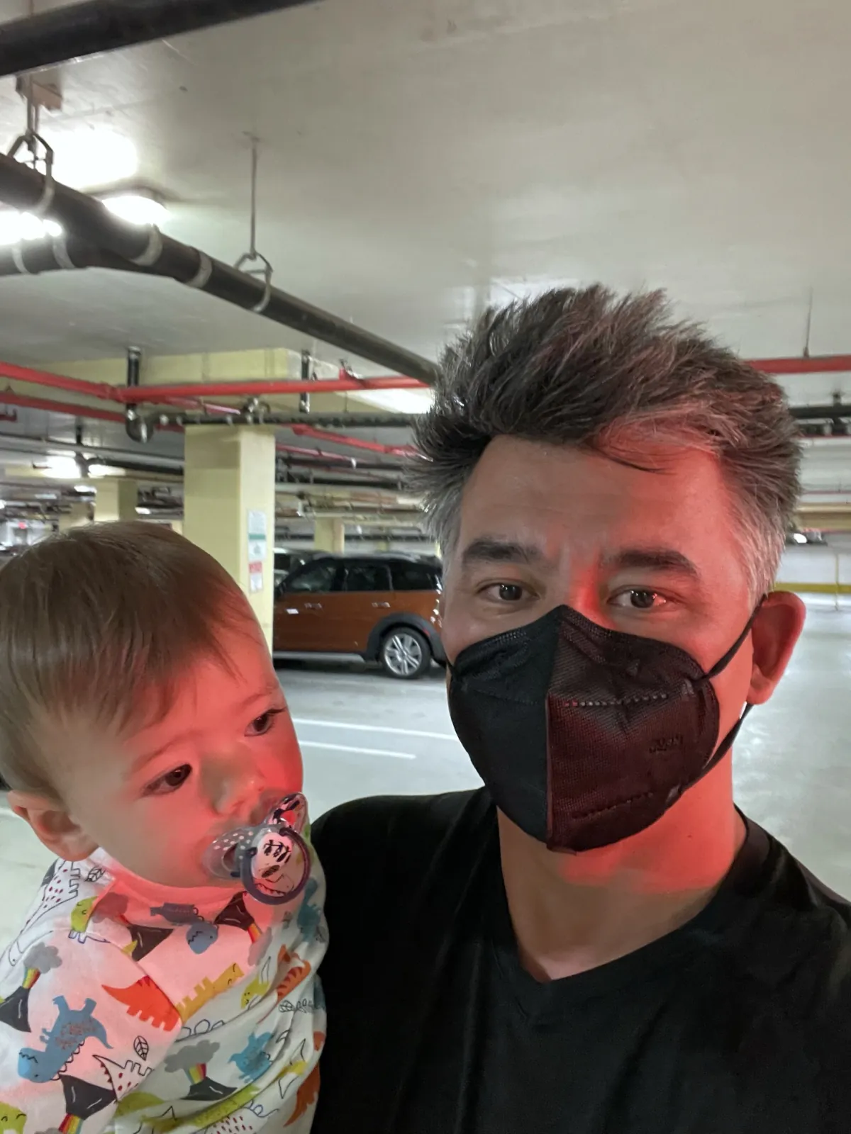 Andrew holding Zoe in a parking garage while wearing a mask