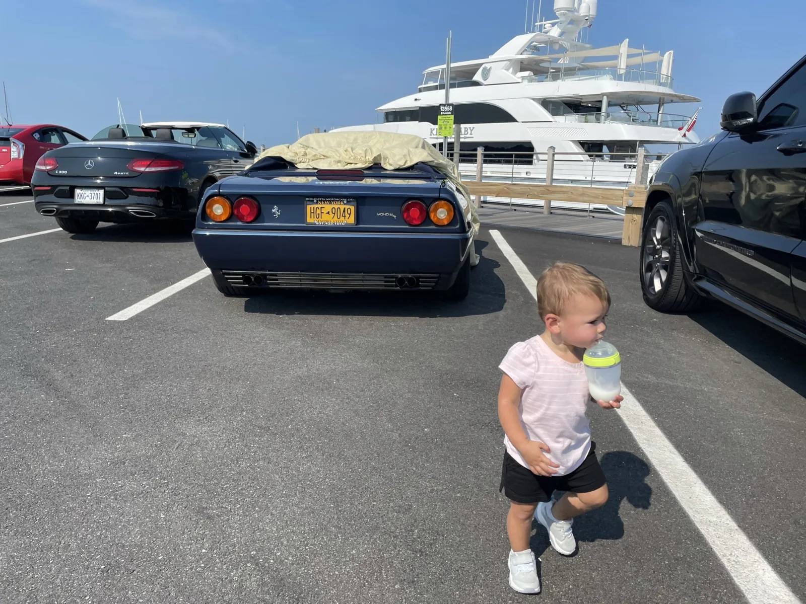 Zoe walking near cars and yachts at a Long Island marina