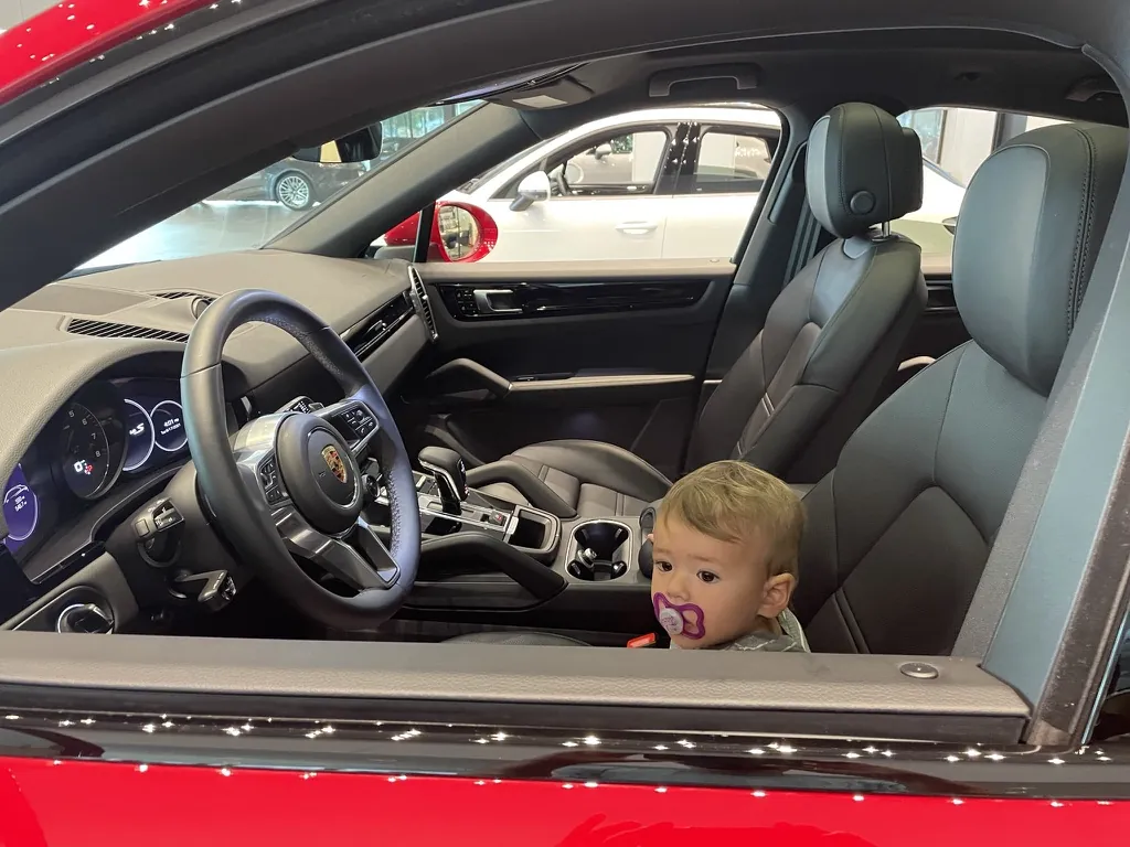 Zoe sitting inside a red Porsche at a dealership