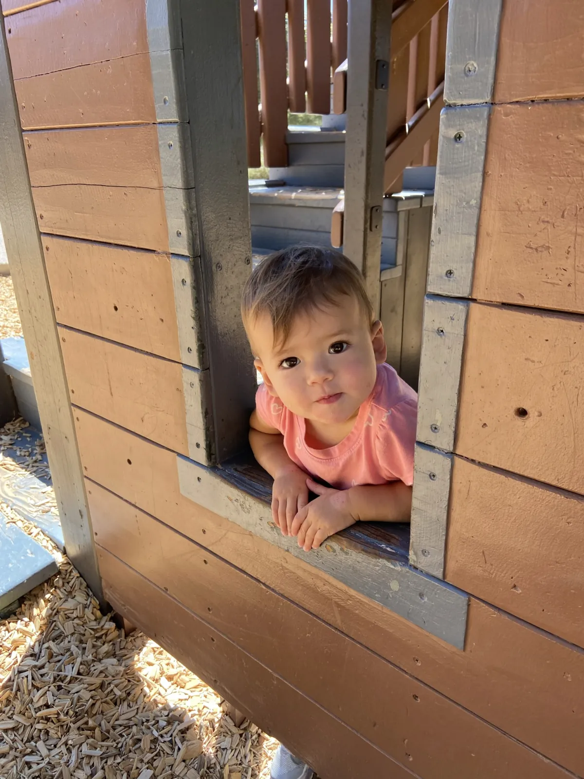 Zoe looking out of a playground playhouse window in Orange County