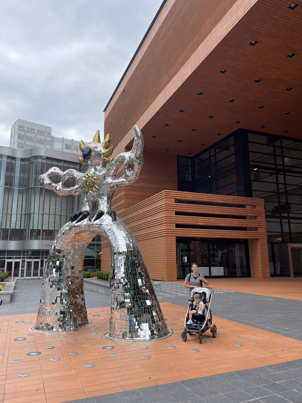Marie with Zoe in stroller by a mosaic sculpture in Charlotte