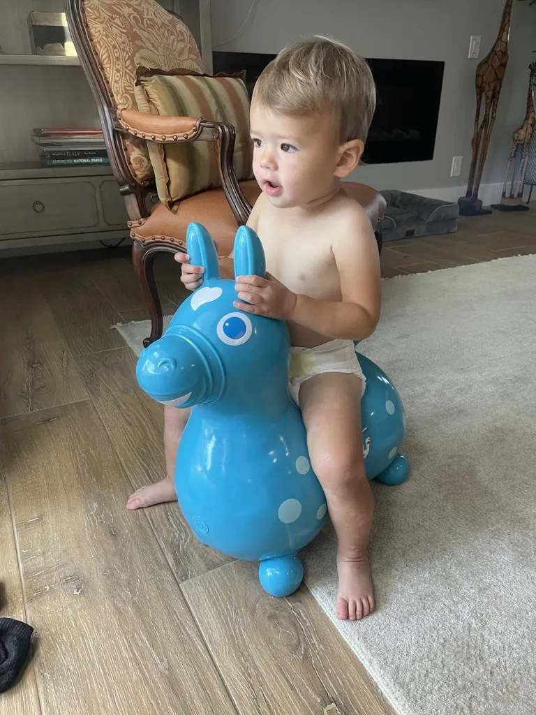 Zoe riding a blue bouncy horse in the living room