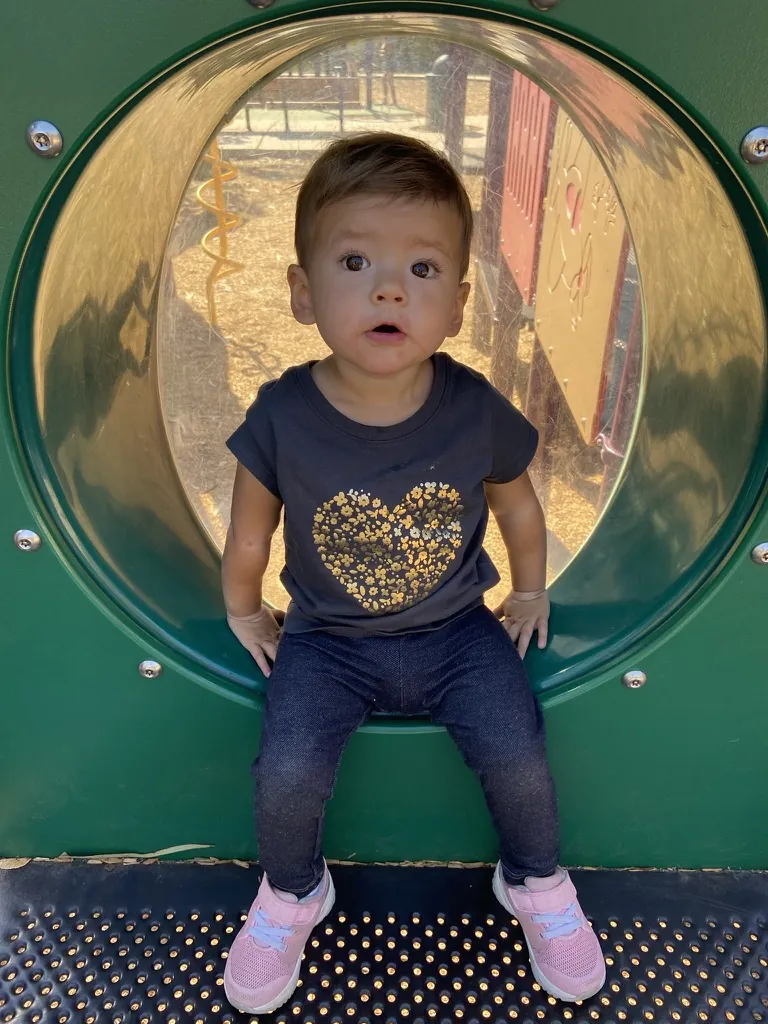 Zoe sitting in a round playground porthole