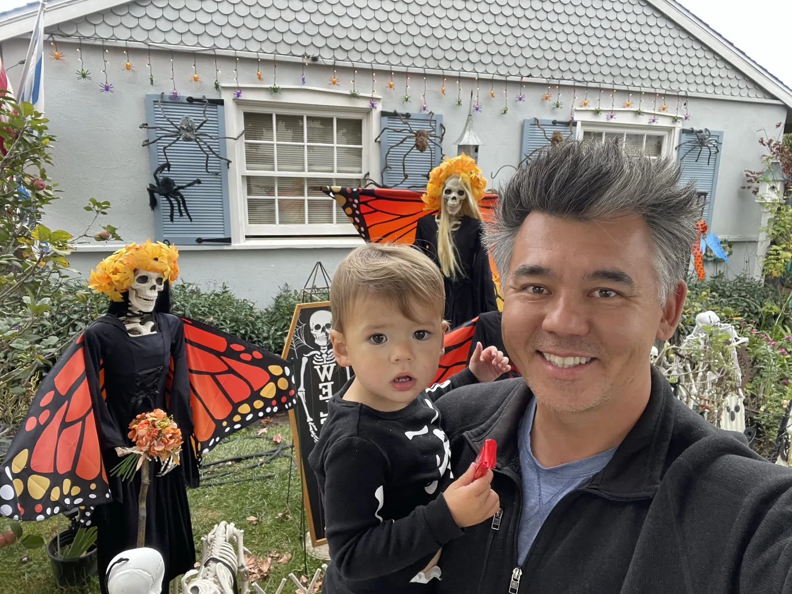 Andrew holding Zoe in front of Halloween butterfly skeleton decorations