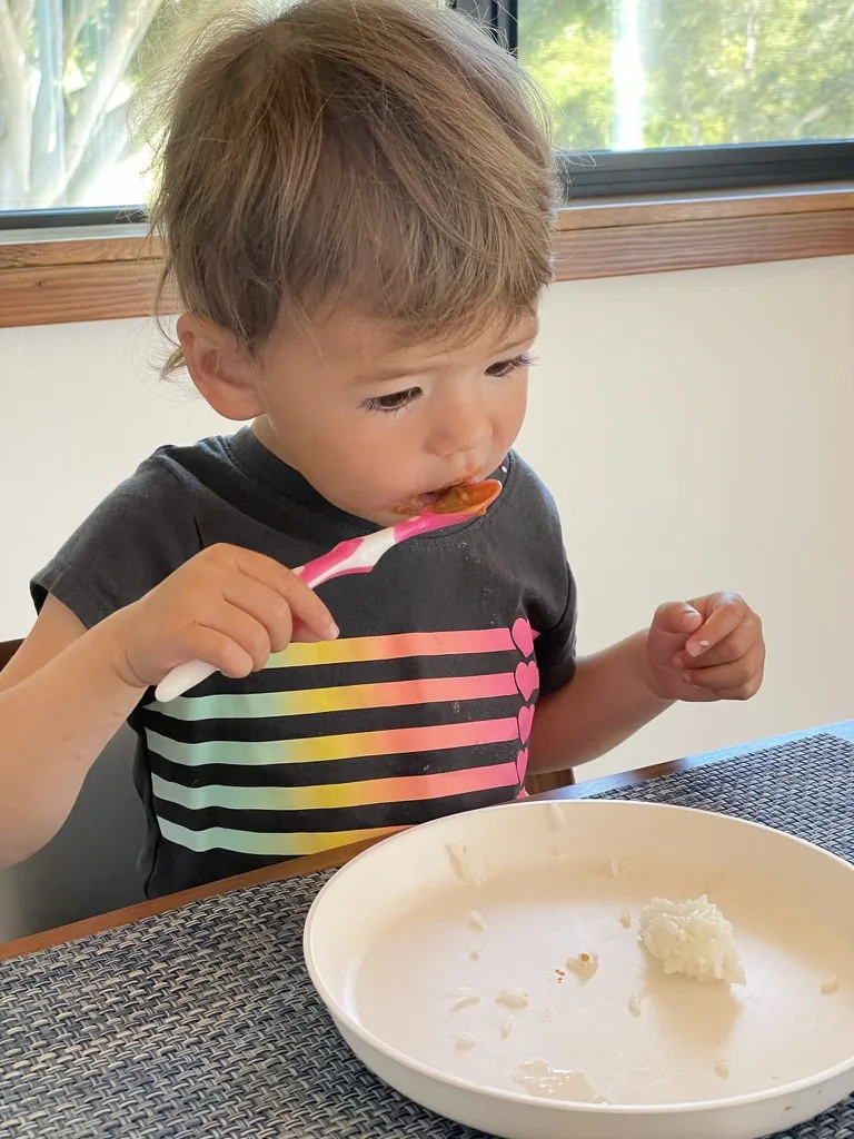 Zoe eating with a spoon at a table