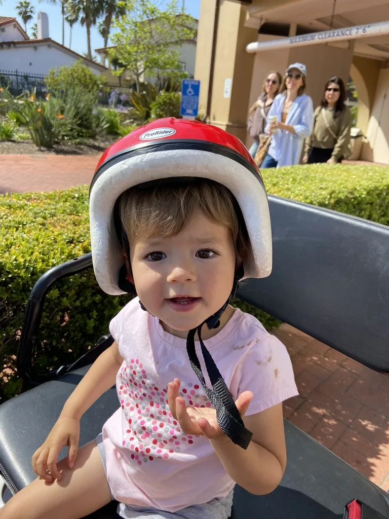 Zoe sitting in a cart while wearing a red helmet