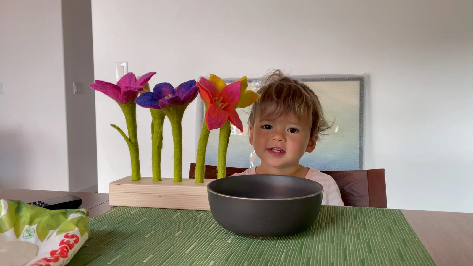 Zoe sitting at a table beside colorful felt flowers and a bowl