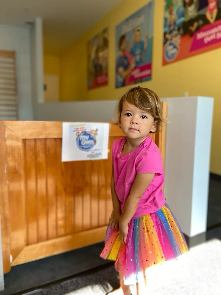 Zoe standing in a rainbow tutu at My Gym