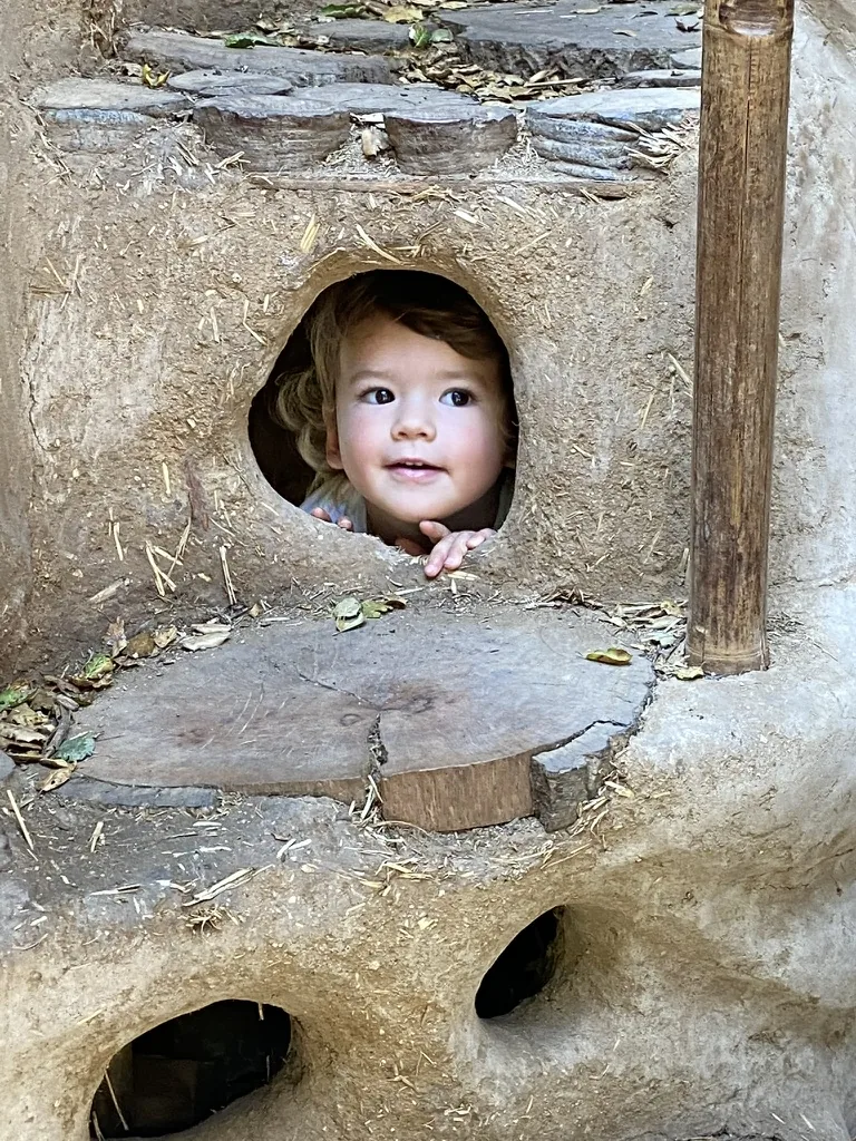Zoe smiling through a small round playground opening