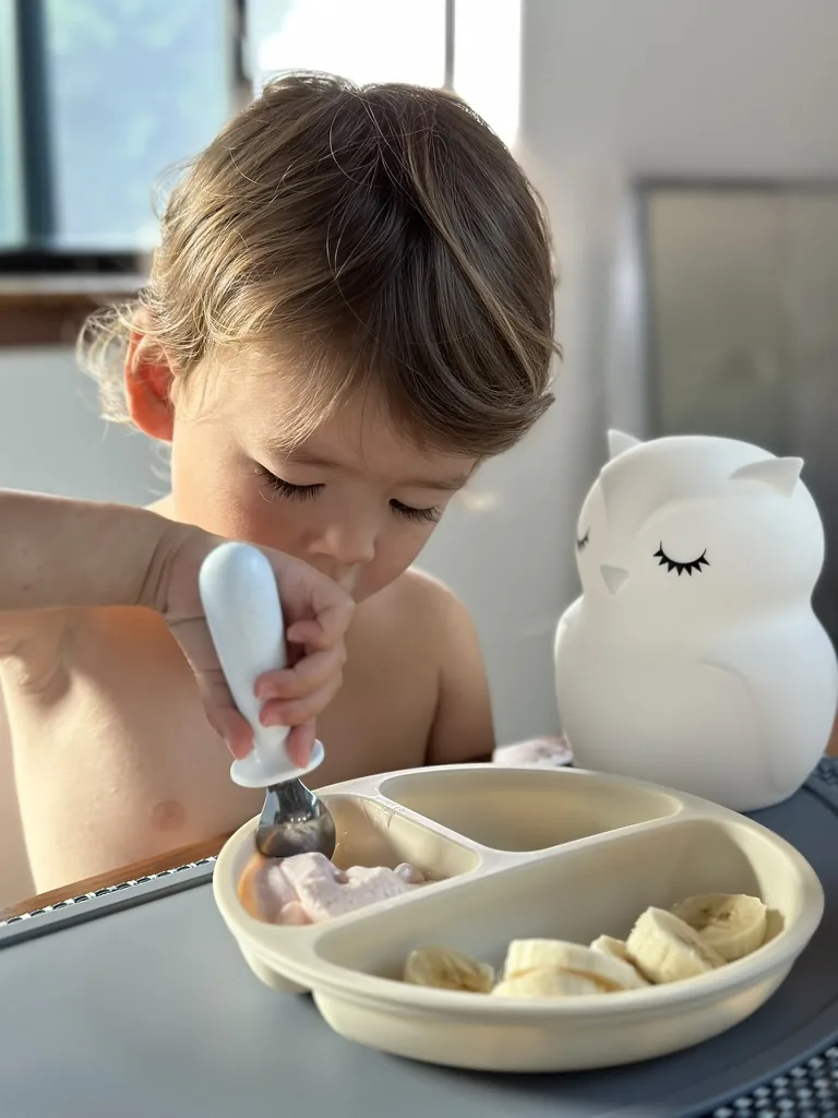 Zoe eating breakfast beside a white owl cup