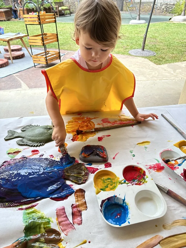 Zoe painting a fish art project with bright colors