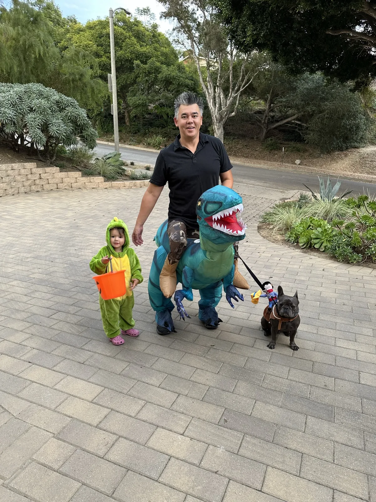 Andrew in a dinosaur costume with Zoe, Francis, and Halloween costumes in the driveway