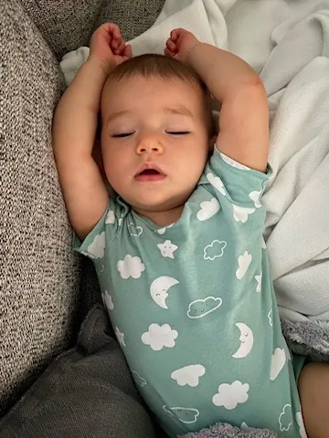Baby Zoe napping in a cloud-patterned onesie