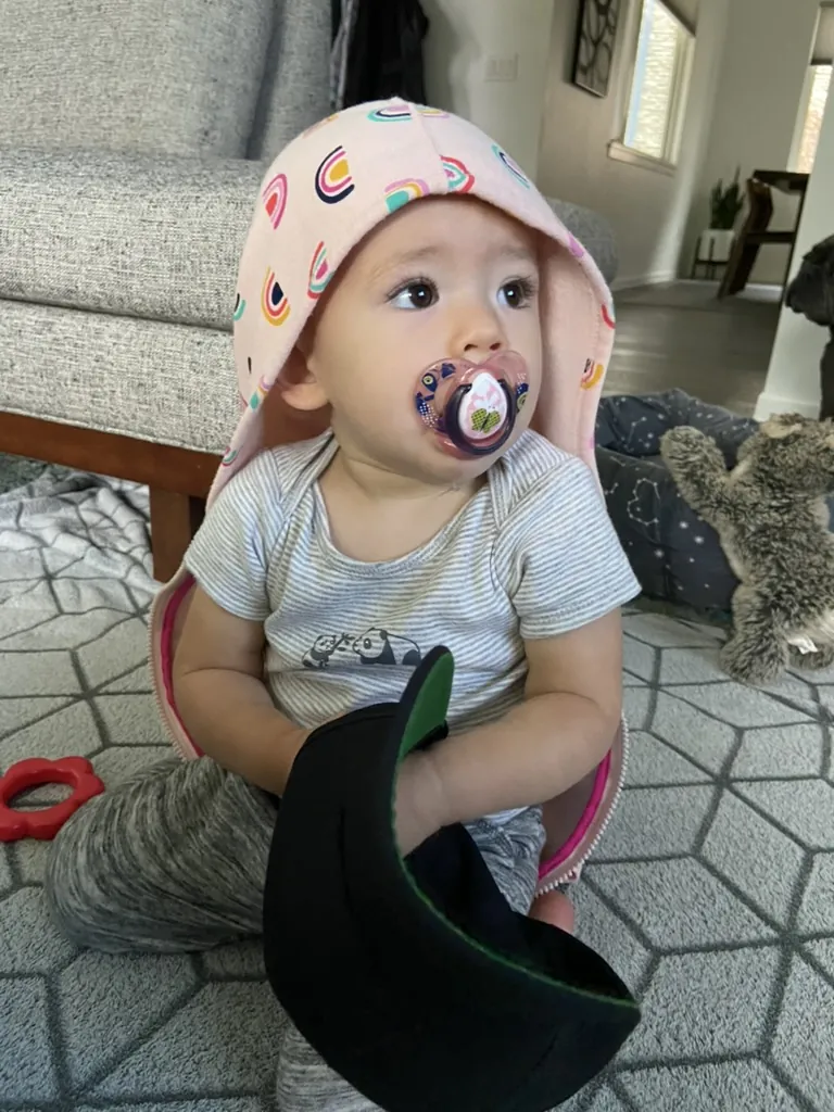 Zoe wearing a rainbow blanket like a hood while holding a shoe