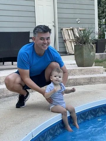 Andrew helping Zoe sit at the edge of a pool